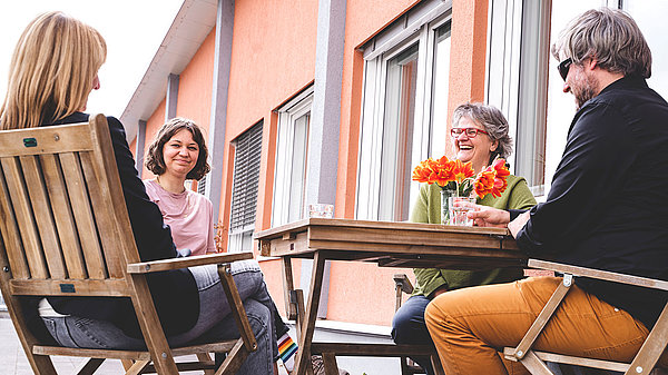 Vier Personen sitzen im Freien an einem Tisch.