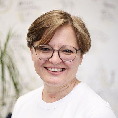 Portait: Frau mit blondem Kurzhaarschnitt und Brille