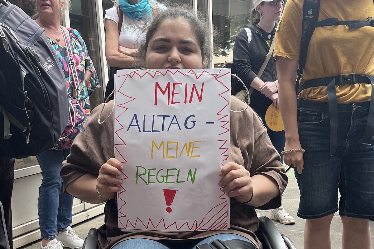  Alternativ Bild per URL einfügen: Kontext des Bildes (optional): Sprache (Mehrauswahl möglich): Deutsch Englisch Türkisch Russisch Polnisch Arabisch Ukrainisch Französisch Spanisch Italienisch Niederländisch Modus: Standard (kurz & bündig) ausführlich hohe Genauigkeit Ich habe die Daten­schutz­erklä­rung gelesen und bin mit der Ver­arbei­tung meiner Daten ein­ver­standen. Alternativer Text Deutsch:  Person im Rollstuhl hält ein Schild mit der Aufschrift 'MEIN ALLTAG - MEINE REGELN!' umgeben von mehreren stehenden Personen in urbaner Umgebung