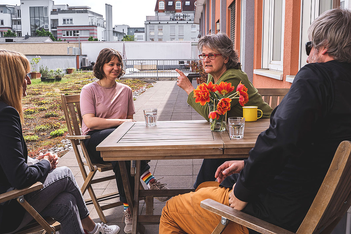 Vier Personen sitzen im Freien an einem Tisch.